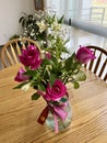 Small arrangement of pink roses with white flowers in a vase with pink bow Royalty Free Stock Photo