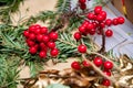 Small artificial red berries in bunches atop mess of green conifer branches and bronze painted leaves on brown background. Royalty Free Stock Photo