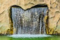 Small artificial waterfall in man made tropical garden. A small decorative waterfall in the garden. Landscape design Royalty Free Stock Photo