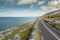 Small asphalt road by Atlantic ocean, Burren National geo park, Ireland. Nobody, Warm sunny day. Beautiful cloudy blue sky. Part Royalty Free Stock Photo