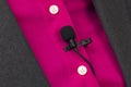 Small audio microphone for voice recording with a clothespin attached to a woman`s shirt