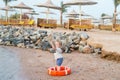 Small baby boy with adorable face with lifebelt on beach