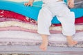 Small baby boy in white trousers sitting on a pile of colorful blankets and mattresses. Happy childhood. Leisure Royalty Free Stock Photo