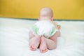 A small baby crawls on a white sheet to a yellow wall. Pink heels of a 2-month-old child learning to crawl and push off Royalty Free Stock Photo