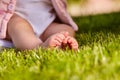 Small baby feet on the green grass at summer sunshiny day in the park.