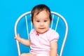 Small baby girl with dark hair and brown eyes mixed rase, kazakh girl and russian on blue background