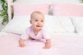 Small baby girl 6 months old crawling on a pink and white bed, looking away, place for text Royalty Free Stock Photo