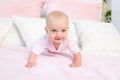 Small baby girl 6 months old crawling on a pink and white bed, looking away, place for text Royalty Free Stock Photo