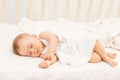 Small baby girl 6 months old sleeping in a white bed, healthy baby sleep