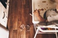 A small baby on a high chair dropped a cup of noodle soup on the wooden floor. The transparent plate is divided into two