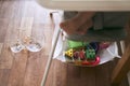 A small baby on a high chair dropped a cup of noodle soup on the wooden floor. The transparent plate is divided into two