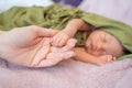 Small baby infant hand holding mother woman finger when sleeping on soft bed. Royalty Free Stock Photo