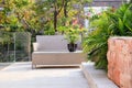 Small backyard area with cane chair and table surrounded by evergreen plants