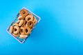 Small bagels in a metal shopping basket on blue background.