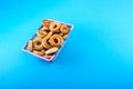 Small bagels in a metal shopping basket on blue background.