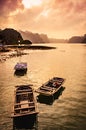 Small bamboo fishing boats in the sea in Ha Long Bay with sunset over the stunning karst stone mountain scenery. Cat Ba Island, Royalty Free Stock Photo