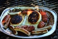Small barbecue accident - cinder camembert cheese leaking to sausages and bratwursts on alluminum plate Royalty Free Stock Photo