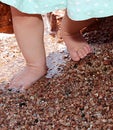 Small barefoot baby legs step on small wet pebble Royalty Free Stock Photo