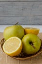 Small basket with fruits. Apples, lemons, carrot on the table.