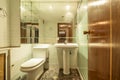 Small bathroom with pedestal porcelain sink, large mirror on the wall and old tiles