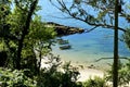 Small beach with clear water, trees, exuberant vegetation and boats. Rocks and sea with green, blue and turquoise colours, sunny d