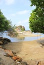 A small beach with a swing underneath a tree on the left and a small island in the middle where you can walk across. Royalty Free Stock Photo