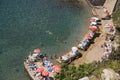 Small beach from top view with umbrellas, people and sunbeds.
