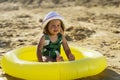 A small beautiful child in a hat is sitting in a small pool Royalty Free Stock Photo