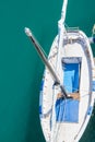 Small Beautiful Empty White and Blue Sailing Boat with Tall Mast Moored at Harbor. Vivid Turquoise Sea. Aerial Top View Royalty Free Stock Photo