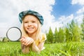 Small beautiful girl with magnifier laying alone