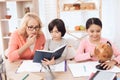 Small beautiful girl is studying globe next to elderly woman who looks at book with little boy. Royalty Free Stock Photo