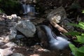 A small but beautiful multi-tiered waterfall with rocks and green foliage