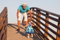 Small beautiful pretty girl is walking on wooden bridge to his father. Royalty Free Stock Photo