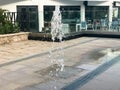 A small beautiful singing fountain in the open air, on the street. Drops of water, jets of water frozen in the air in flight again Royalty Free Stock Photo