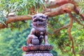 Small beautiful statue of mythical chinese lion guard on blurred pine tree background in Chi Lin Nunnery park,Hong Kong.
