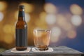 Small beer bottle with a glas on a table with a blur bokeh