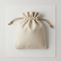 A small beige drawstring bag with a textured fabric surface is centered on a plain white Royalty Free Stock Photo
