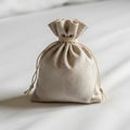 A small beige drawstring pouch sits on a light-colored fabric surface. The bag is made Royalty Free Stock Photo