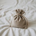 A small, beige drawstring pouch sits on a soft, cream-colored fabric surface. The Royalty Free Stock Photo