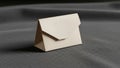 Beige paper envelope stands upright on a textured gray fabric Royalty Free Stock Photo