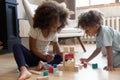 Small biracial children play with wooden blocks at home