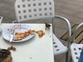 A small bird, a sparrow eats a delicious pizza from a table in an outdoor cafe on the street Royalty Free Stock Photo