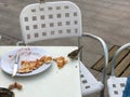 A small bird, a sparrow eats a delicious pizza from a white table in an outdoor cafe on the street Royalty Free Stock Photo