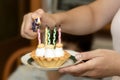 Small birthday cupcake on a plate in the hands lighting candles