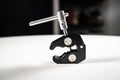 Small black aluminum camera cinema rig screw clamp sitting on a white table Royalty Free Stock Photo