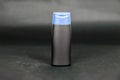 Small black blank bottle with blue cap on dark background Royalty Free Stock Photo