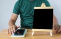 Small black board on wooden table,blank blackboard and man with smartphone