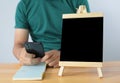 Small black board on wooden table,blank blackboard isolated and man used smartphone Royalty Free Stock Photo