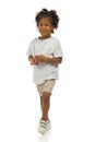 Small black boy in shorts and shirt is looking away. Full length, isolated Royalty Free Stock Photo