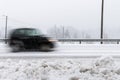 Small black car in motion blur on the road in winter landscape, with snowy weather. Royalty Free Stock Photo